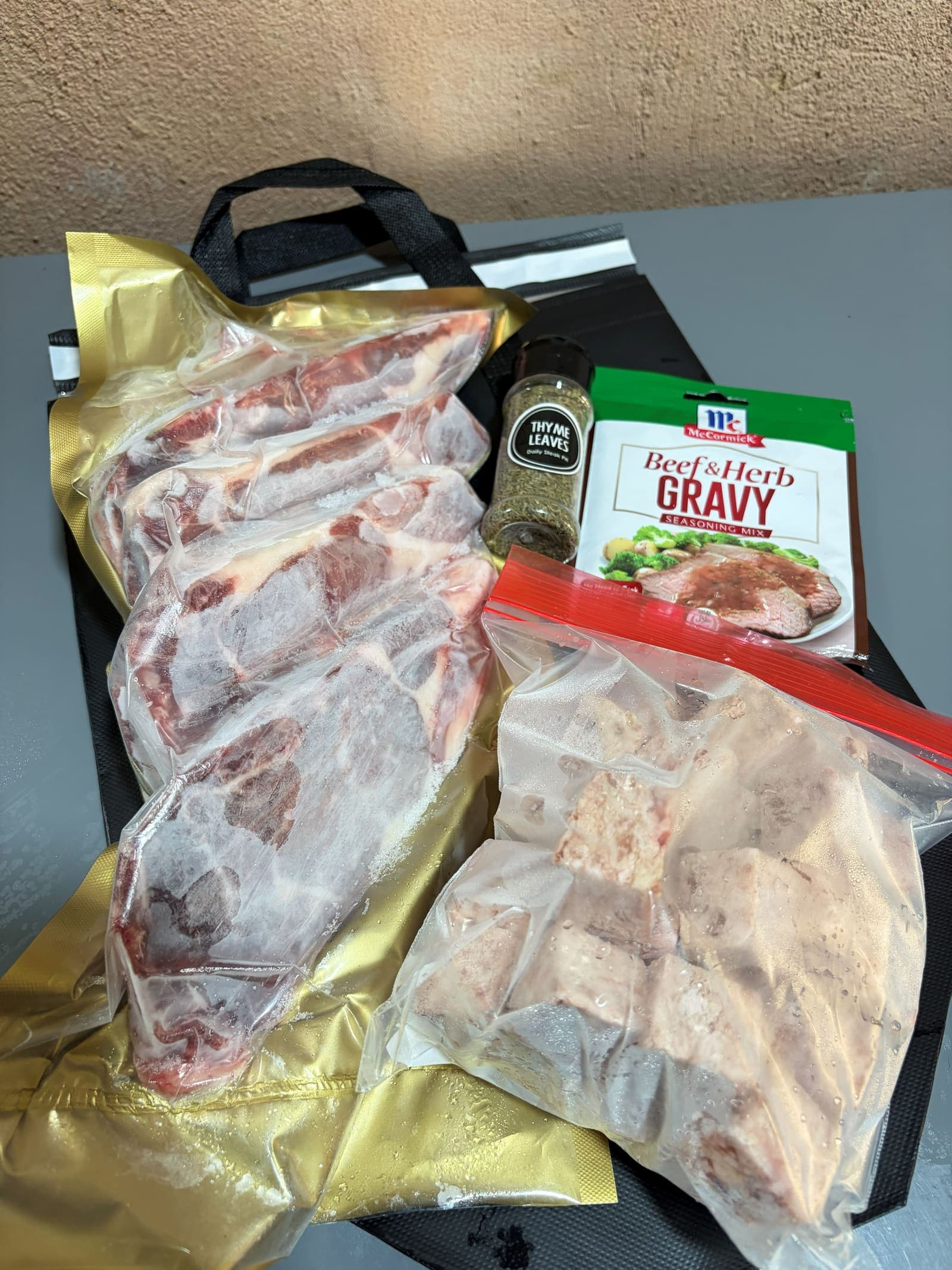 Bone-in butter-aged cuts in the gold pack beside a bag of wagyu cubes, thyme leaves and beef and herb gravy