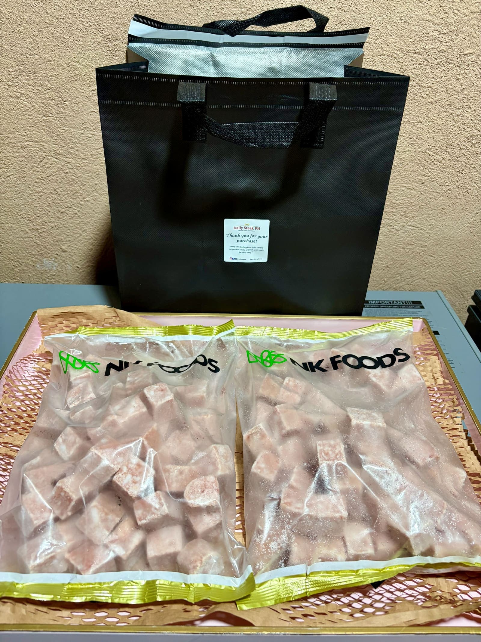 A packed Daily Steak PH order: two NK Foods wagyu cube packs beside the insulated bag they travel in, sealed with a thank-you sticker